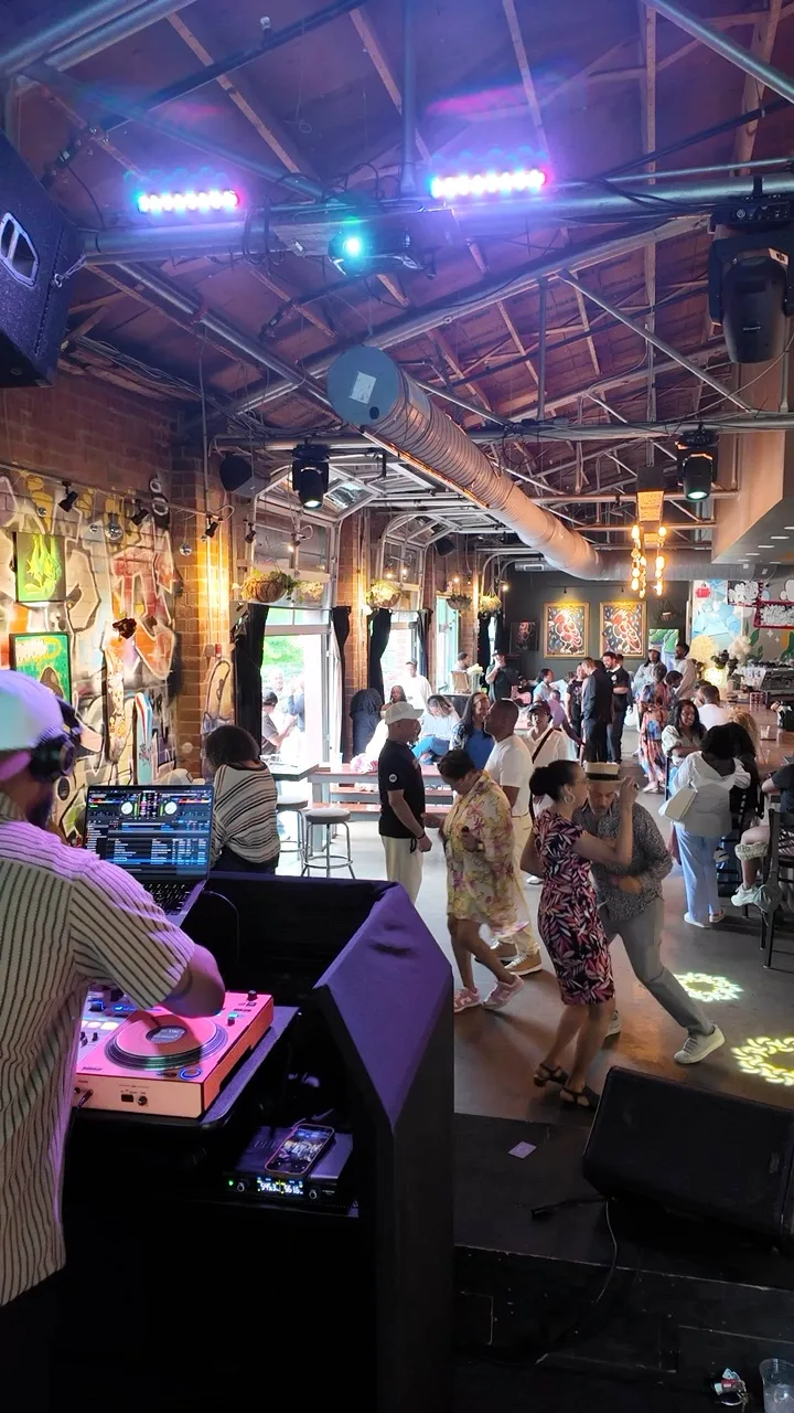 Guests dancing together in a colorful event space, seen from beside the DJ decks