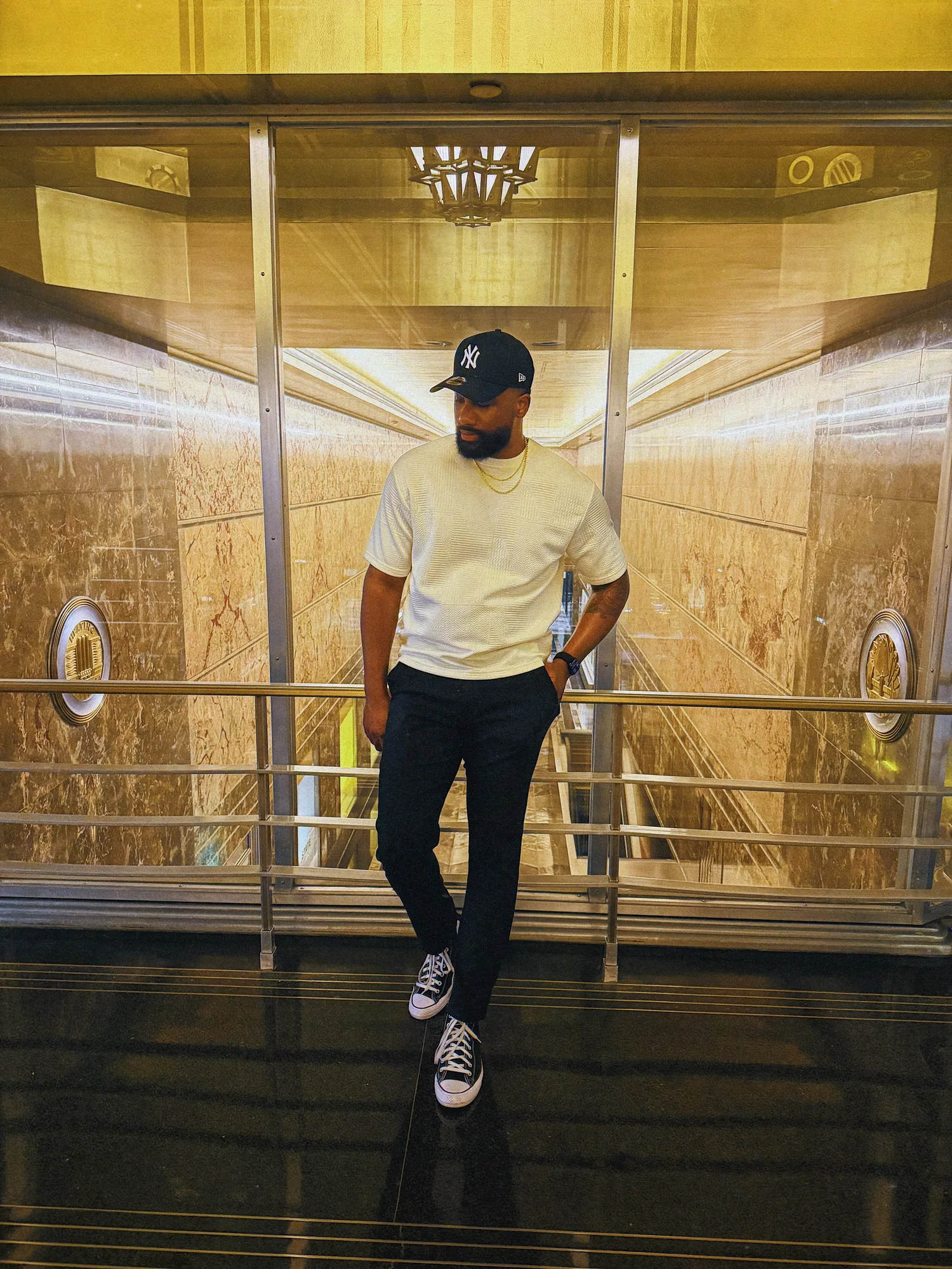 Keon NaVarr standing on a stairway surrounded by warm gold-toned architecture