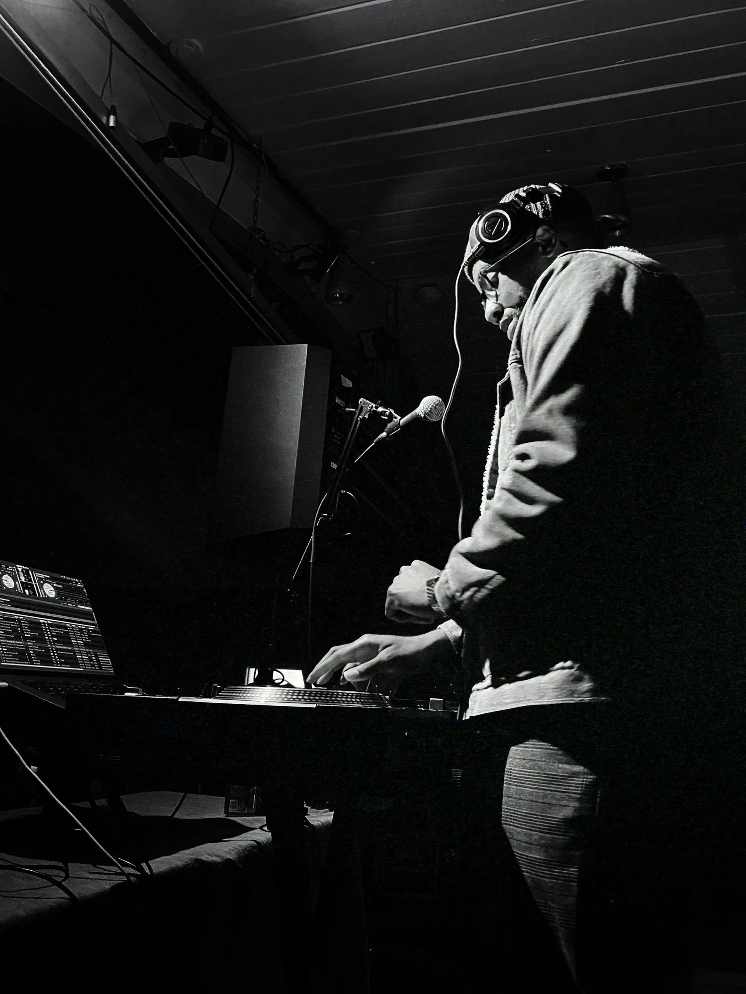 Keon NaVarr performing at a DJ setup, photographed in black and white