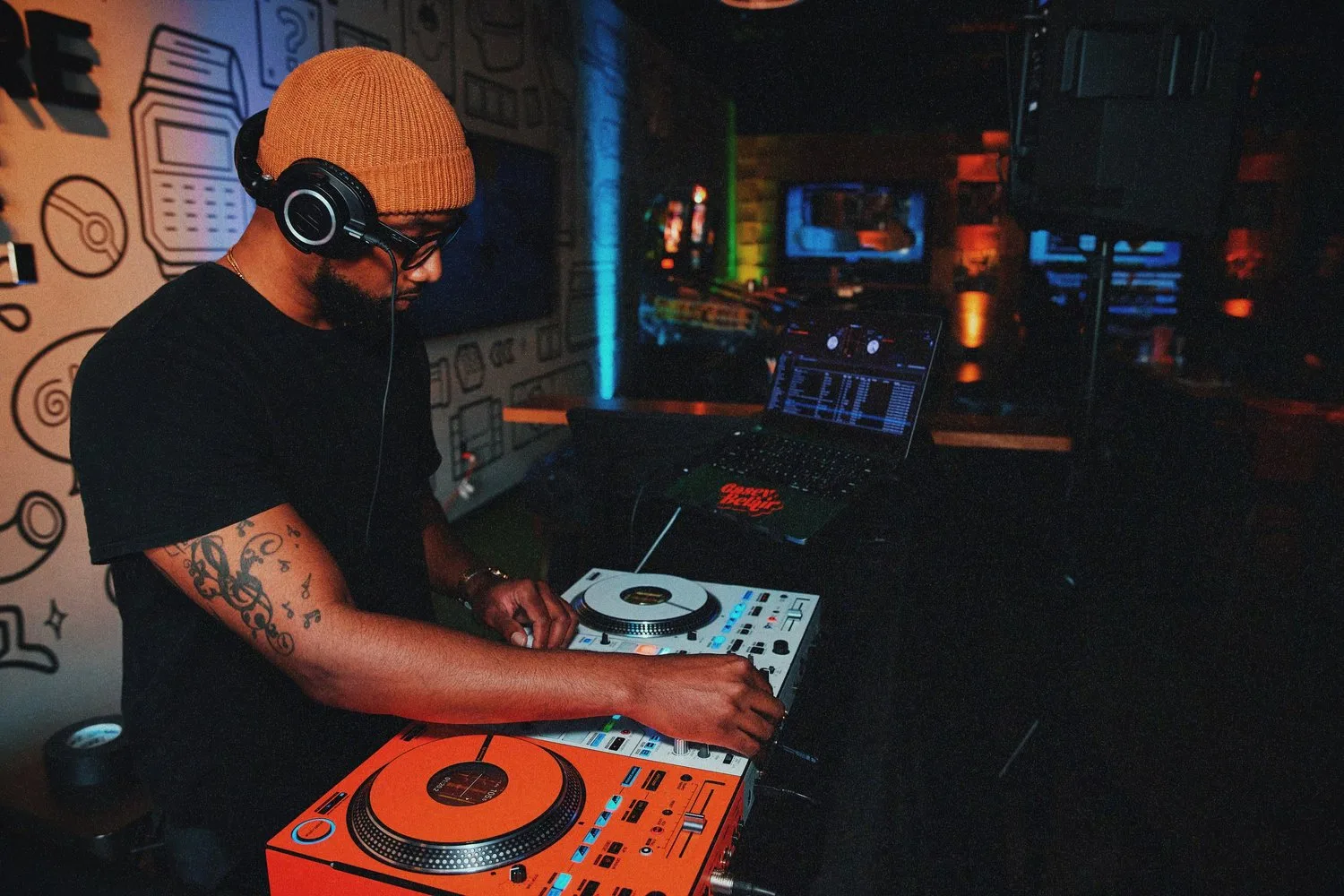 Keon NaVarr in headphones at a colorful DJ setup