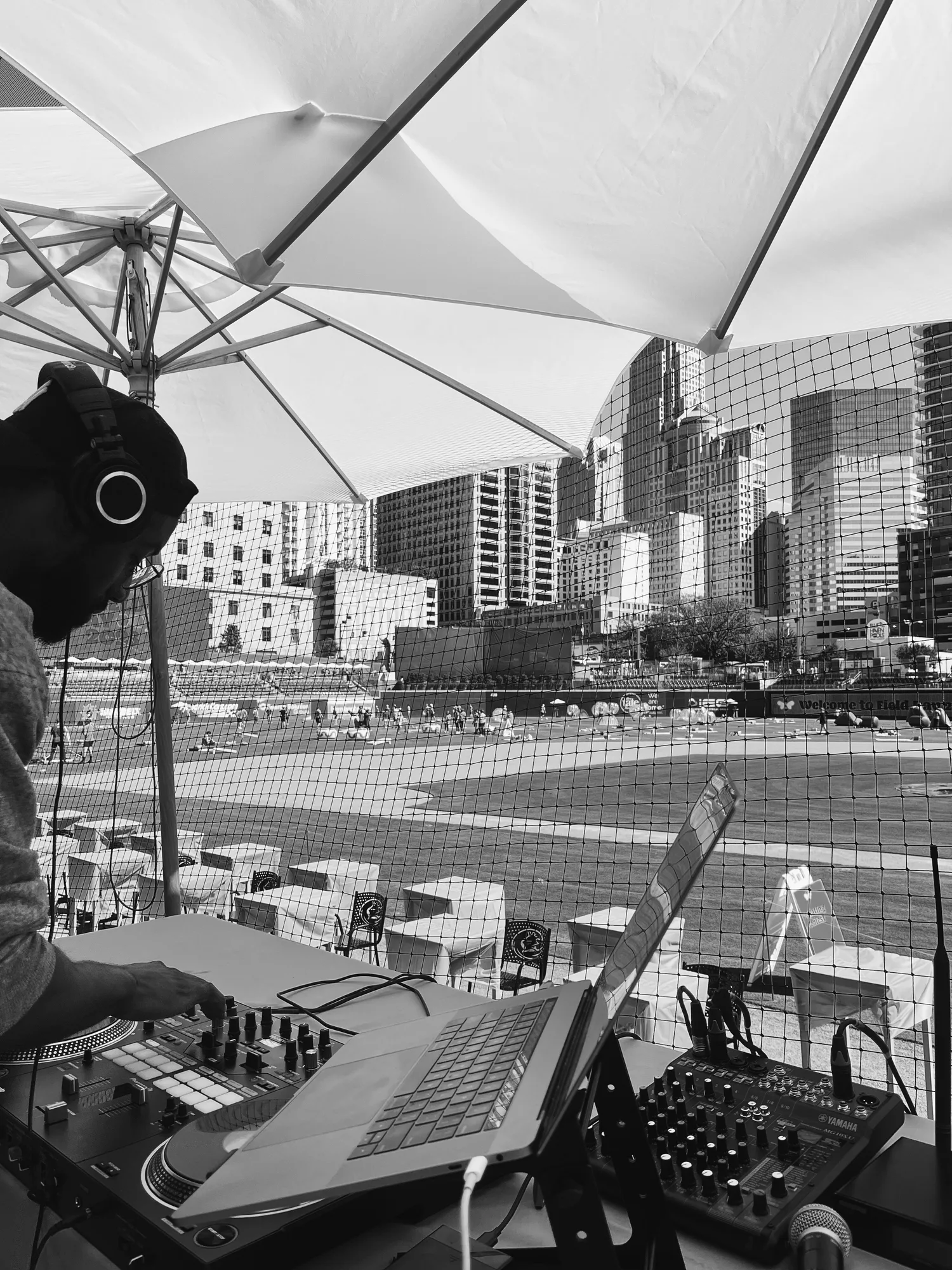 Keon NaVarr working at the DJ decks overlooking a baseball field and city skyline
